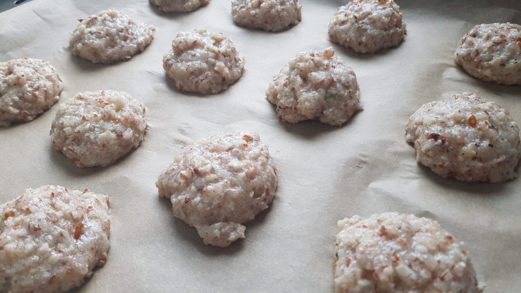 Bakepapir med boller av rå deig plassert utover brettet.